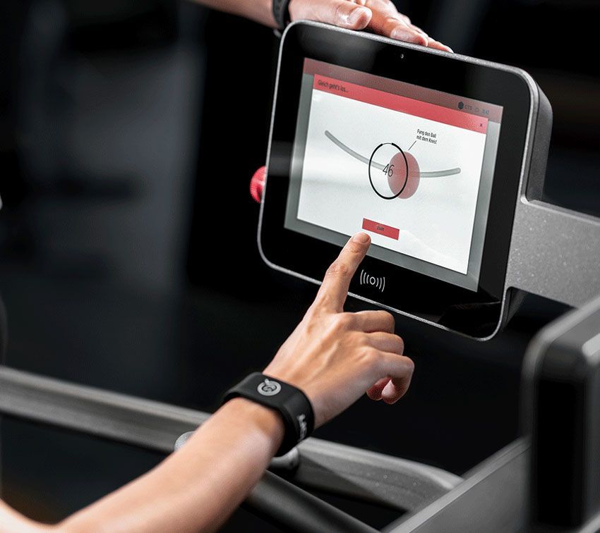 Person bei der Interaktion mit einem Touchscreen-Display an einem Trainingsgerät